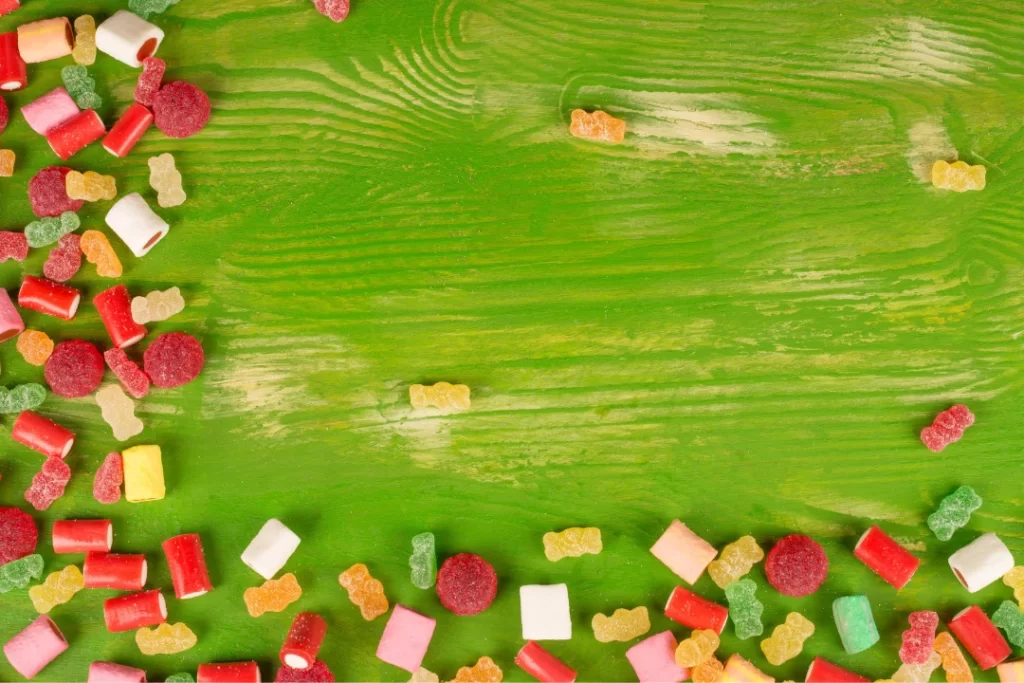 A lot of gummies on a green wooden table.