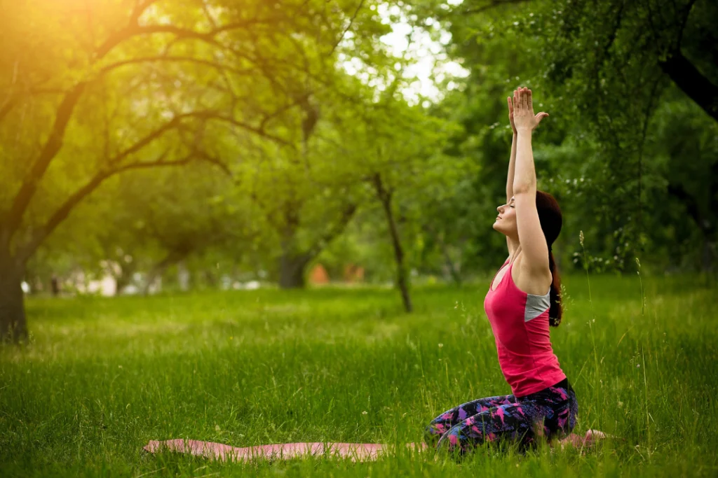Young woman doing yoga in green forest. 